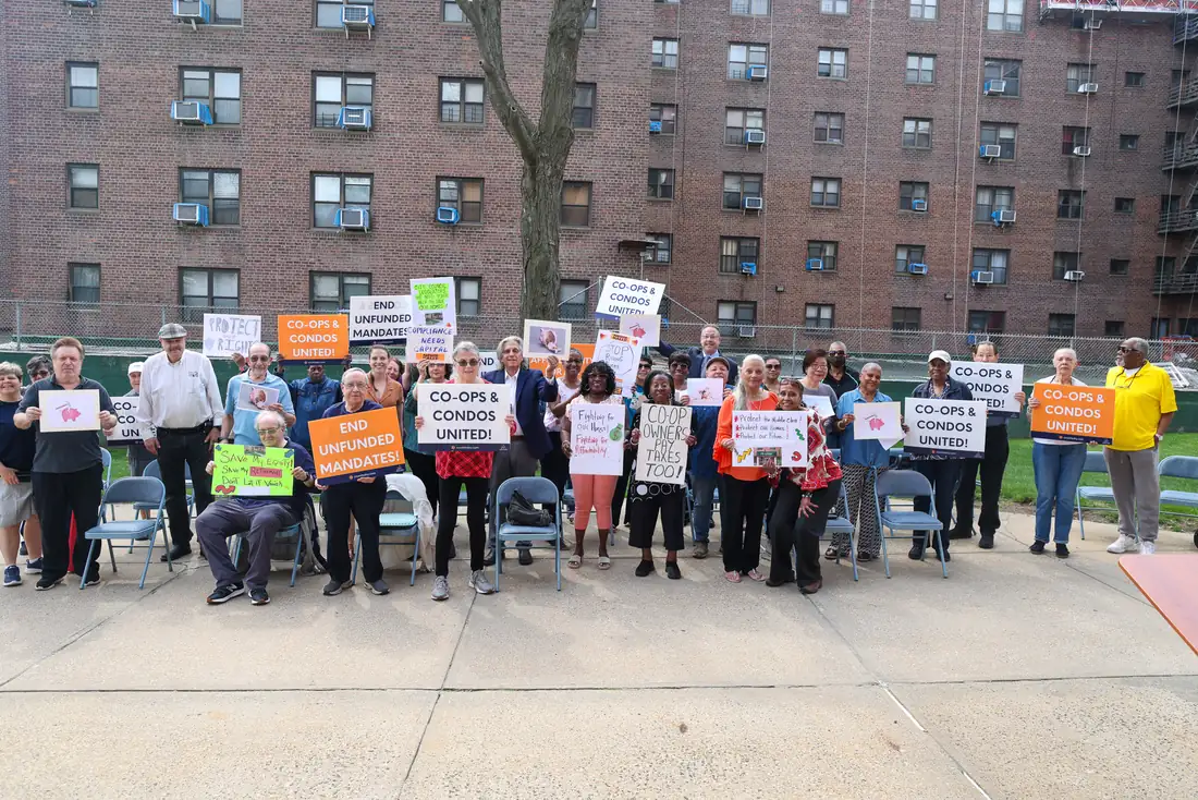Members of Co-ops & Condos United holding signs outside a Queens co-op complex